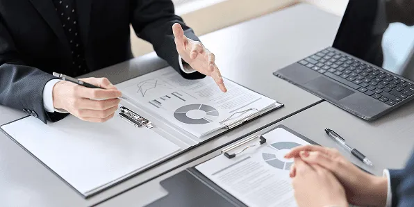 男性2人がPCと資料を手元に打ち合わせています。